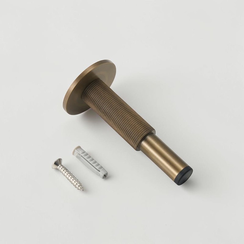Aged brass knurled door stop with rubber bumper, mounting screw and wall anchor