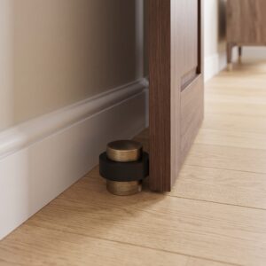 Aged Brass floor mounted door stop with rubber bumper beside a wooden door
