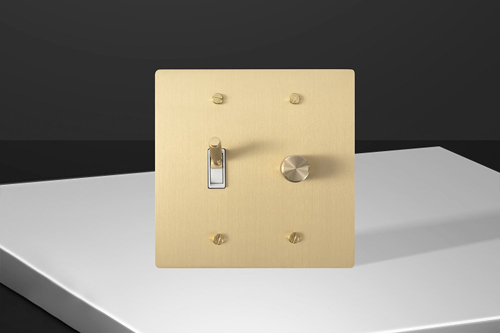 Brass toggle with a white surround beside a brass rotary lighting dimmer.